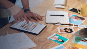 Desainer kreatif jasa website development memilih palet warna di tablet sambil menyusun konsep desain dan foto untuk pembuatan website profesional.