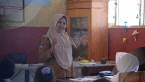 Seorang guru sedang menjelaskan hasil analisis data pendidikan kepada siswa di kelas untuk meningkatkan kualitas pembelajaran