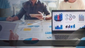 Marketing specialist menganalisis data kampanye dengan tim menggunakan laptop, tablet, dan grafik pemasaran.