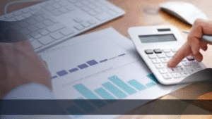 Tangan seseorang sedang menggunakan kalkulator di atas meja kerja dengan grafik dan keyboard, menunjukkan analisis data keuangan sebagai bagian dari strategi marketing kit digital.