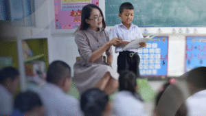 Guru membimbing siswa yang sedang membaca di depan kelas, mencerminkan suasana pembelajaran Ramah Anak bersama Konsultan
