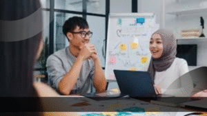 Tim sedang berdiskusi di ruang meeting dengan papan strategi di belakang, menggambarkan Peran Product Specialist dalam mengkoordinasikan ide dan strategi produk.
