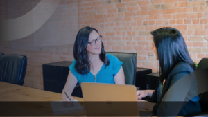 Dua profesional berdiskusi di ruang kerja dengan laptop dan catatan, menggambarkan strategi konsultan pendidikan dalam optimalisasi platform pembelajaran digital.
