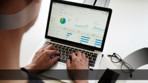 Seorang profesional sedang menganalisis grafik performa situs melalui dashboard Google Analytics di laptop.